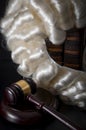 Judicial system and legal code concept with judge powdered wig hanging on old law books next to a judgeÃ¢â¬â¢s wooden gavel or mallet